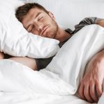 Handsome young man sleeping in bed